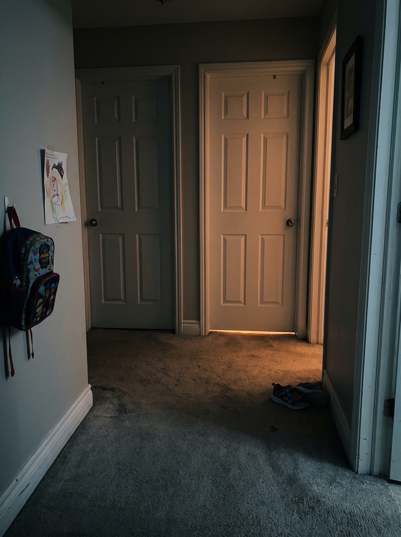 A dim hallway with two closed kids' bedroom doors, the house finally quiet